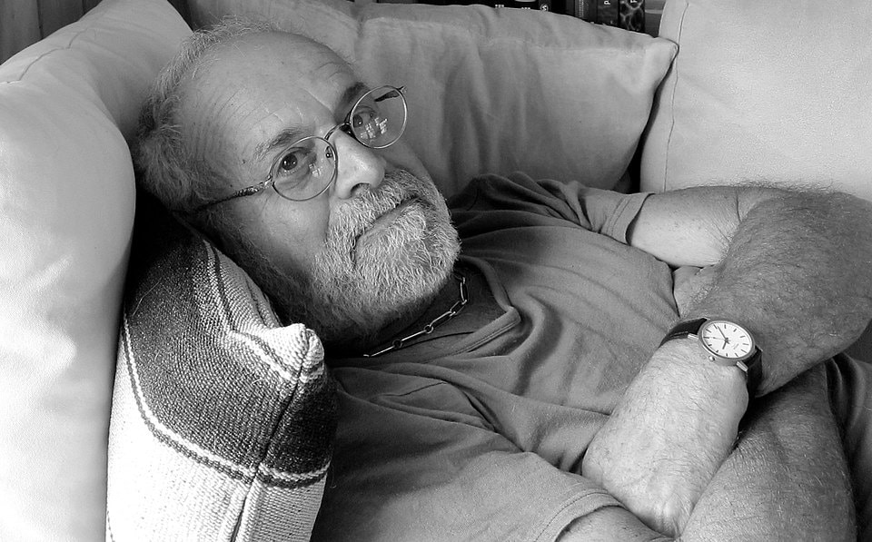 Bearded man relaxing on a sofa with cushions.
